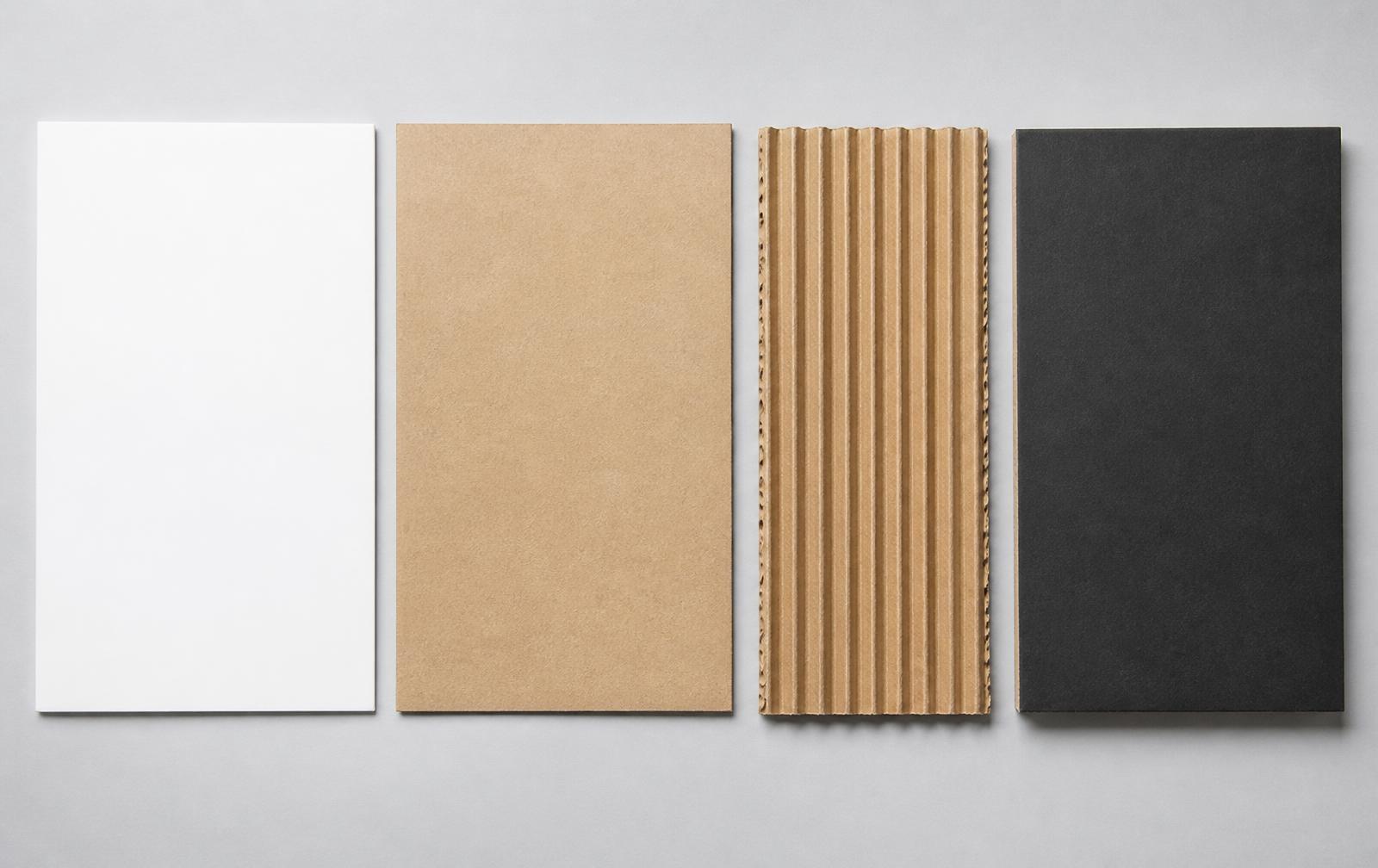 White cardboard, brown kraft paperboard, corrugated fluted board and thick black rigid board samples laid side by side