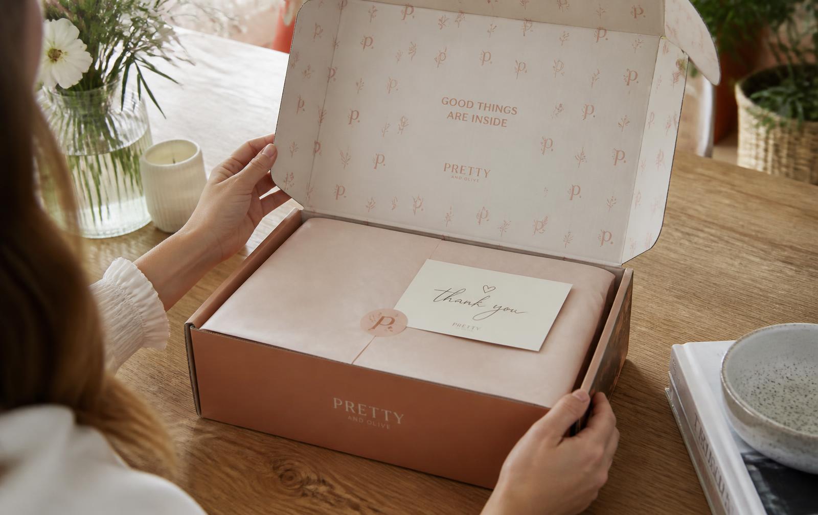 Customer opening a branded mailer box with printed interior, tissue paper and a thank-you card inside