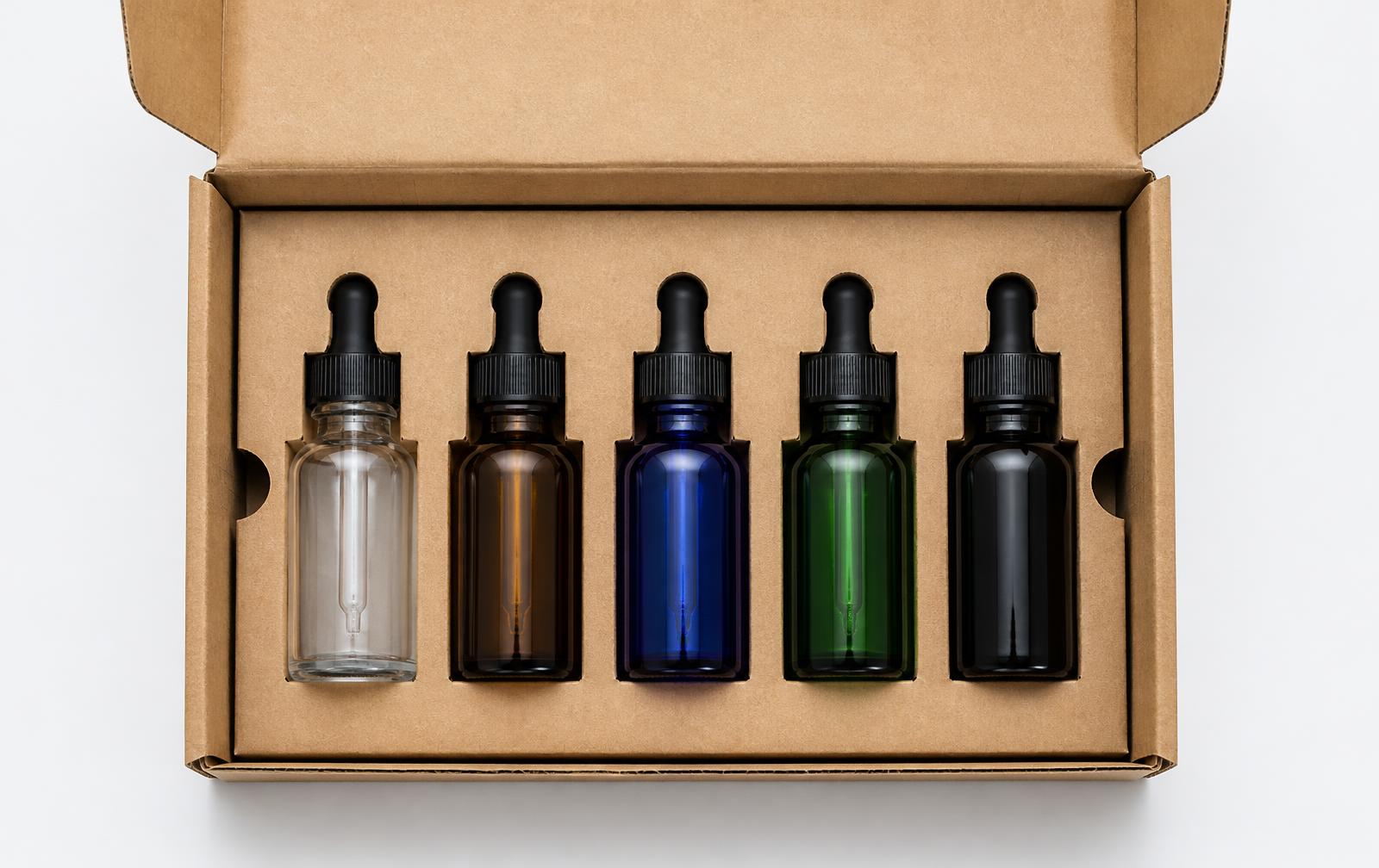 Five glass dropper bottles held in place by fitted cardboard inserts inside a custom corrugated box